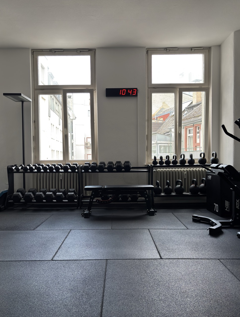 Trainingsfläche mit Kurzhantel-Ständer, Kettlebells und Hantelbank vor den Fenstern des Gyms in der Frankfurter Innenstadt
